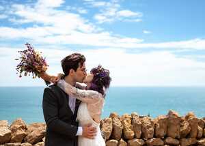 wedding couple kissing in front of dry stone wall overlooking sea wedding couple kissing in front of dry stone wall overlooking sea