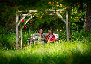 two visitors sitting on a wooden swing seat at abbotsbury subtropical gardens